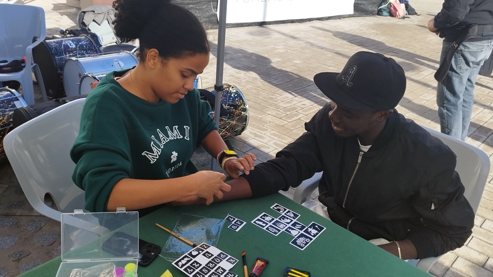 Personas haciendo tatuajes en celebración por el dia de los derechos humanos