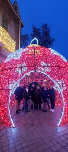 Personas posando debajo de una bola de navidad