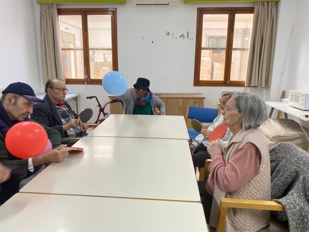 Personas mayores jugando al tenis de mesa con globos