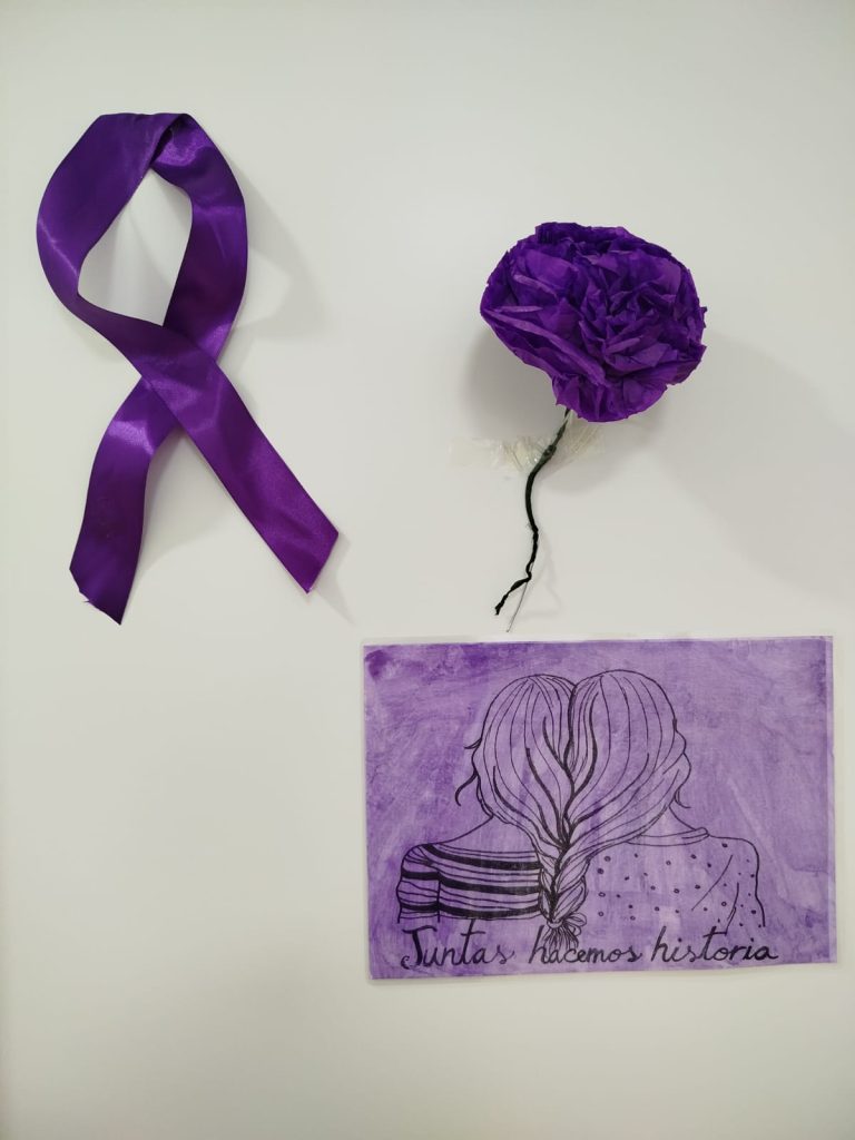 Foto de una lazo morado con una flor del mismo color y dibujo de unas trenzas unidas